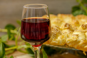 Homemade pastry with sesame and cheese and glass of wine of blackberry. Table with vintage bamboo mat and liana vine in the background.