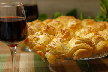 Homemade pastry with sesame and cheese and glass of wine of blackberry. Table with vintage bamboo mat and liana vine in the background.