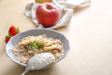 Plate with tasty oatmeal and banana slices on wooden table