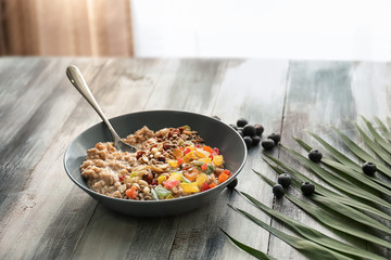 Plate with tasty oatmeal, nuts and succades on wooden table