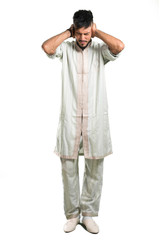 A full-length shot of a Arabic young man wearing typical arab clothes covering both ears with hands...