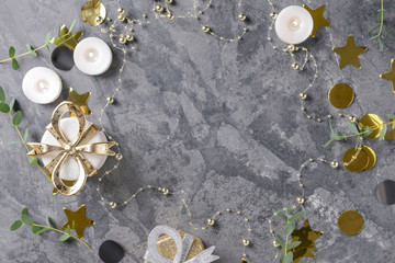 Frame made of burning candles with eucalyptus branches and gift boxes on grey background