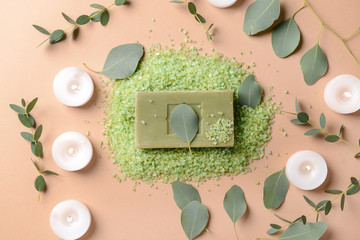 Burning candles with eucalyptus leaves, sea salt and soap bar on color background