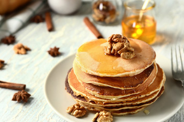 Stack of hot tasty pumpkin pancakes with honey and walnuts on plate