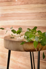 Burning candles with eucalyptus branches on wooden table