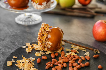 Delicious caramel apple with nuts on slate plate