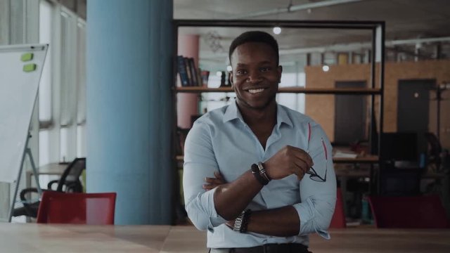 office worker, businessman takes off his glasses and looks up at the camera. African American portrait