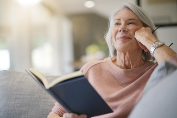  Senior woman reading on couch at home