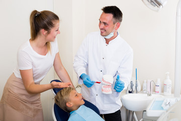 Dental in white is telling to young boy and mother about healthcare