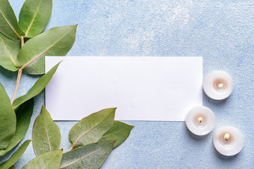 Burning candles with eucalyptus branches and blank card on color background