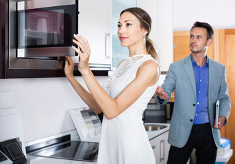 Couple choosing microwave in household appliance section