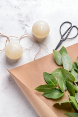 Burning candles with eucalyptus leaves and paper on light background