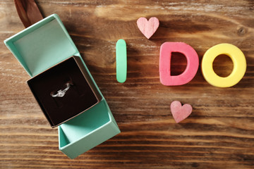Box with engagement ring and inscription I DO on wooden  table