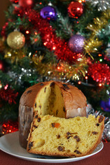panettone tagliato, una fetta pronta da mangiare, sullo sfondo addobbi di natale