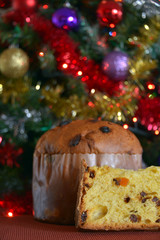 panettone tagliato, una fetta pronta da mangiare, sullo sfondo addobbi di natale