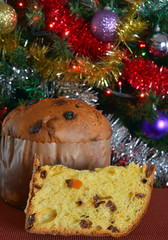 panettone tagliato, una fetta pronta da mangiare, sullo sfondo addobbi di natale