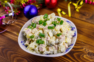 Traditional Russian festive salad Olivier and New Years decorations on wooden table