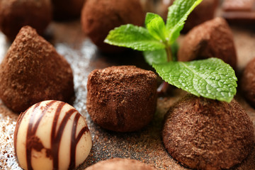 Tasty chocolate truffles with mint on table, closeup