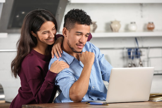 Young couple with laptop in kitchen