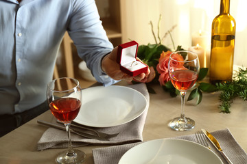 Young man proposing to his beloved at romantic date in restaurant