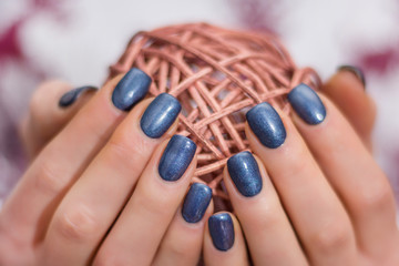 Female with navy blue nails polish holding decorative hank. Manicure concept image. Close up,...
