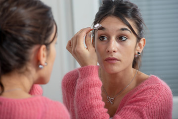 young brunette woman putting makeup in the mirror