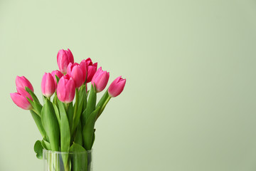 Vase with beautiful tulips on color background