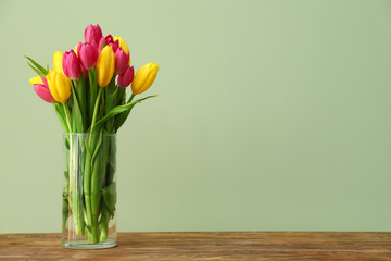 Vase with beautiful tulips on wooden table