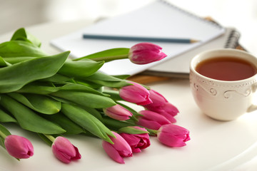 Fototapeta na wymiar Beautiful tulips with cup of tea on white table