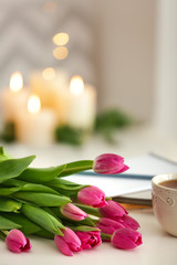 Beautiful tulips with cup of tea on white table