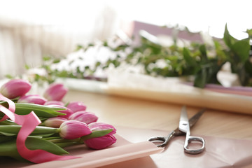 Obraz na płótnie Canvas Beautiful tulips with scissors on table of florist