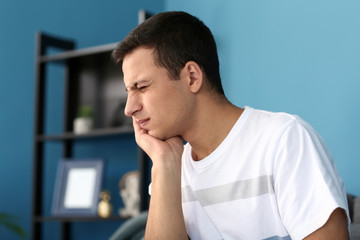 Young man suffering from toothache at home