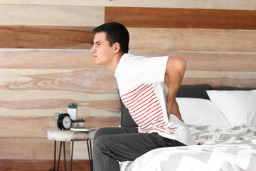 Young man suffering from back pain at home