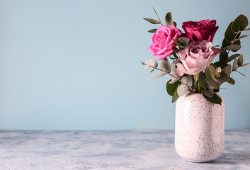 Beautiful bouquet of roses in vase on color table