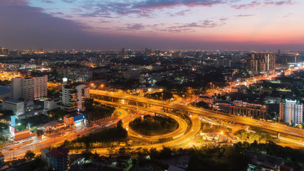 Aerial top view highway road intersection roundabout or circle with cityscape and beautiful sky for transportation, distribution or traffic background.