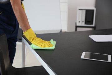 Janitor wiping table in office