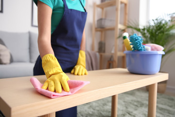 Female janitor wiping table in flat