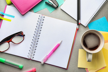 Open notebook, cup of coffee and school stationery on table, top view