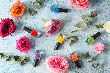 Beautiful roses with bottles of nail polish on color background