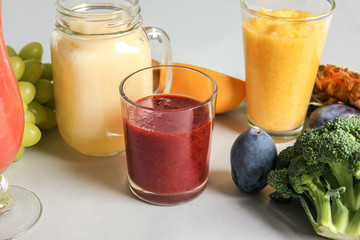 Glassware of tasty colorful smoothies with ingredients on light table