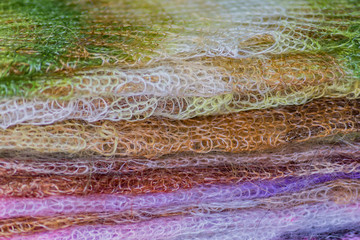 Stack of knitted downy scarfs for background. Russian famous Orenburg shawls. Crochet, pattern.