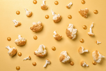 Painted cauliflower with golden drops on color background