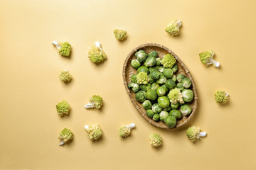 Wicker tray with Brussels and Romanesco cabbage on color background