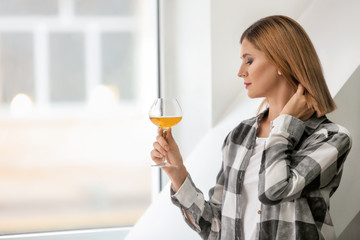 Beautiful woman with glass of white wine near window