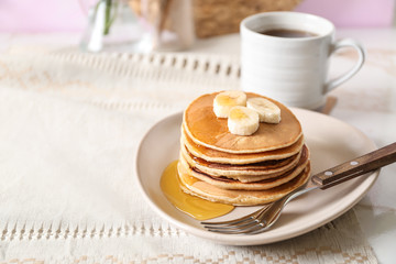 Stack of hot tasty pancakes with honey and banana slices on plate