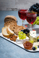 cheese plate, fresh ciabatta, grapes and two glasses of red wine, vertical