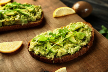 Delicious avocado toasts on wooden board, closeup