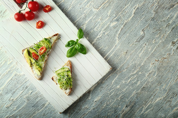White wooden board with delicious avocado toasts on table, top view