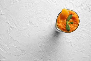 Glass of tasty orange smoothie on white table