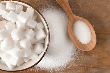 Bowl with sugar cubes on wooden table